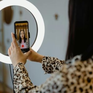 A Woman Using Smartphone and Ring Light