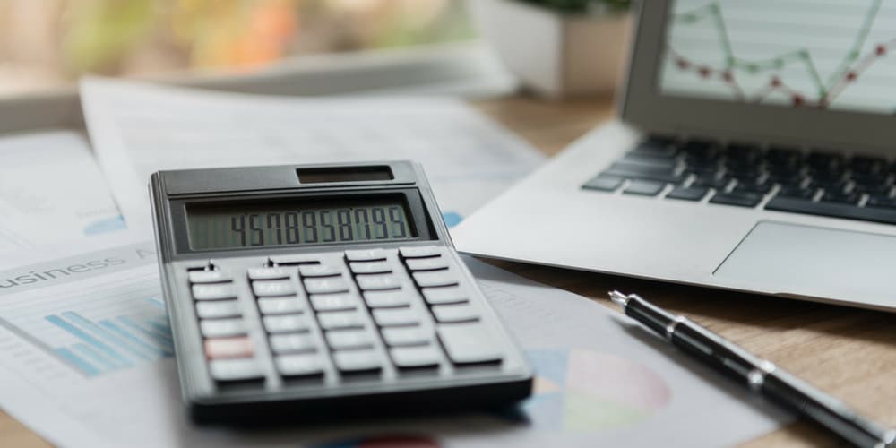 Laptop, calculator, pen, and paper reports representing accounting for small business.