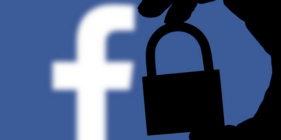 Hand holding padlock over Facebook logo representing historic pay wall updates in past Facebook algorithm changes.