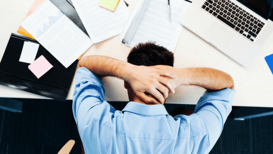 man at desk job with business casual attire and macbook stressed 