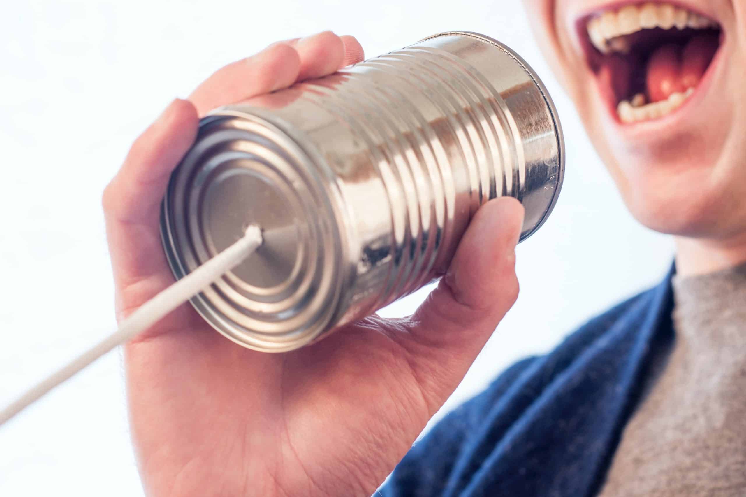 image of a person speaking into a tin can on a string